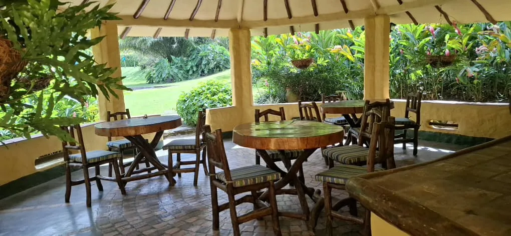 Mesas y sillas en un caney rodeado de jardines